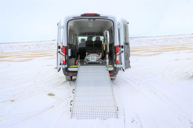 Ford Transit van with wheelchair ramp and stretcher access for medical transportation, parked in a snowy parking lot in Winnipeg Manitoba