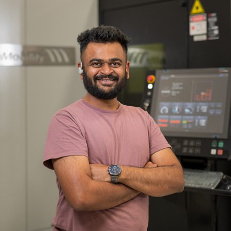 Man smiling for his photo beside a machine