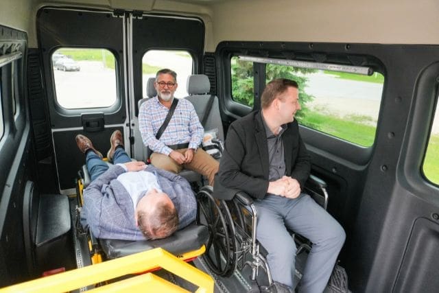 A person in stretcher, a person in a wheelchair, and one person in a seat in an accessible patient transfer van from MoveMobility